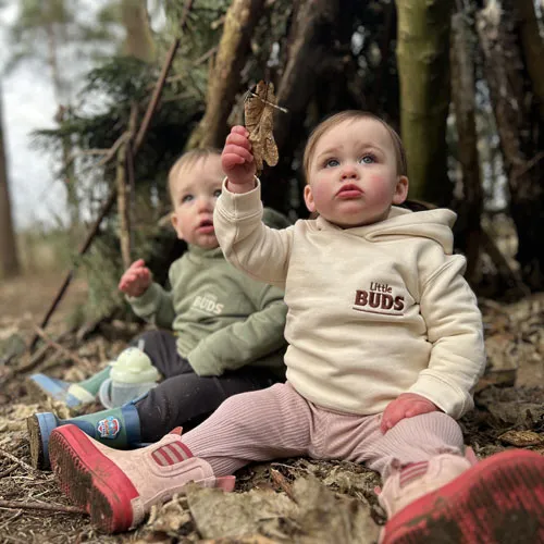 Two Little Buds in a woodland denone holding up a leaf