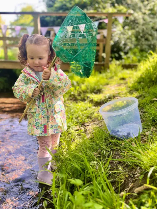 Little girl exploring a small stream with a fishing net